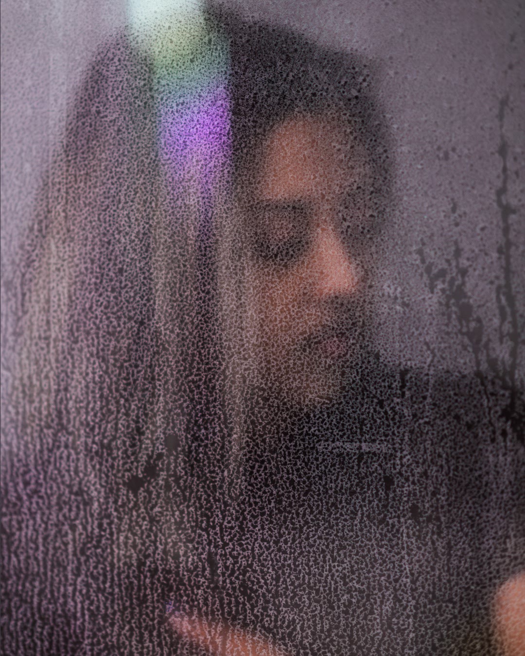 Becca Rashid behind rain-streaked glass